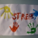 Plakat mit bunt gedruckten Handabdrücken und dem roten Schriftzug "STREIK".