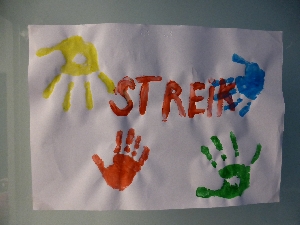 Plakat mit bunt gedruckten Handabdrücken und dem roten Schriftzug "STREIK".