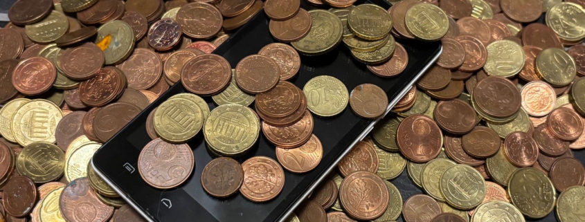 Mobiltelefon in einem Haufen Münzen liegend.